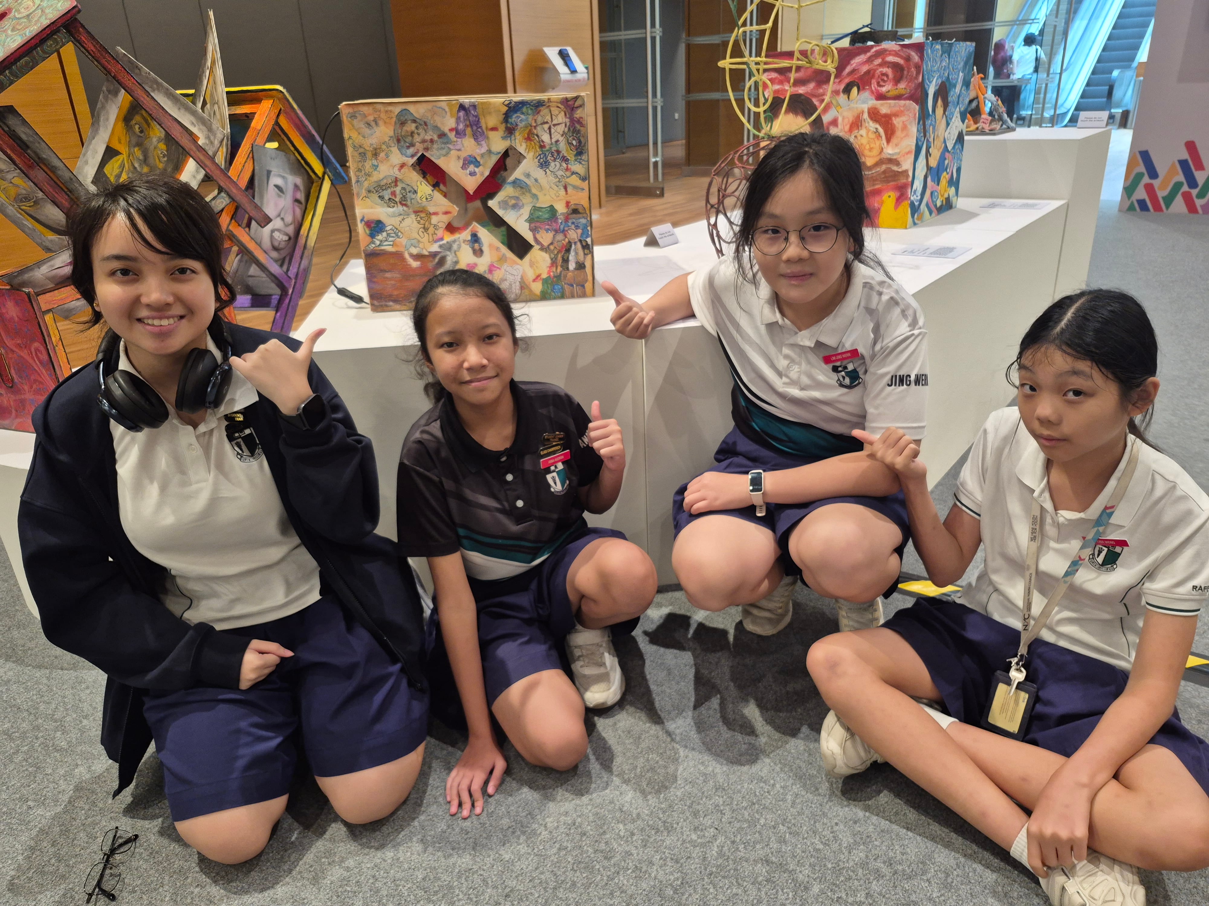 A group of 4 students posing in front of some art installations at an art gallery.